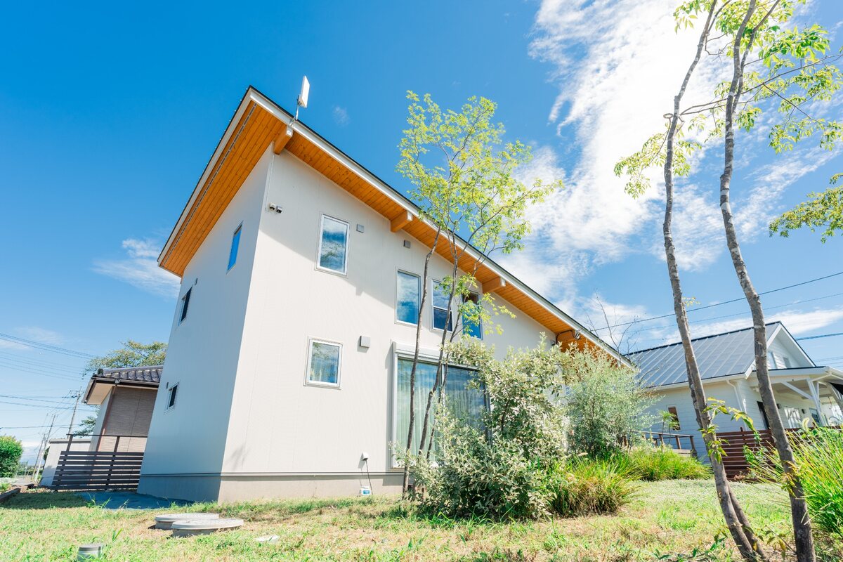 青空の下に建つ、深い軒と木部が印象的な住まい